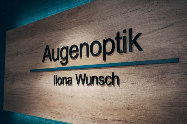 Schild von Augenoptik Ilona Wunsch an der Wand im Geschäft